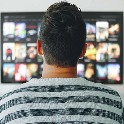 man looking at movie titles on a tv