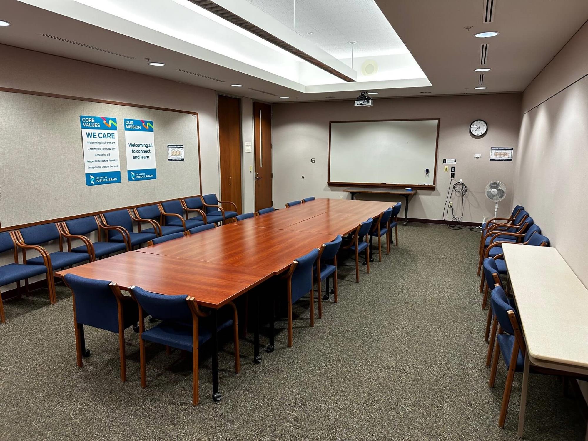 room with a large table, chairs, and a whiteboard