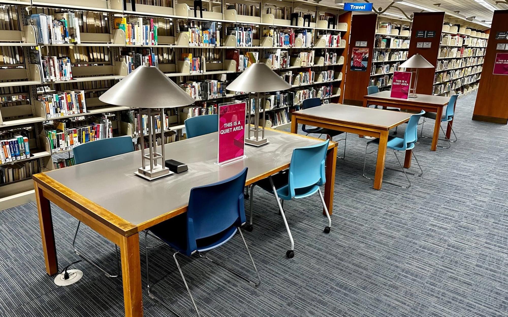 2 large tables and chairs surrounded by book shelves