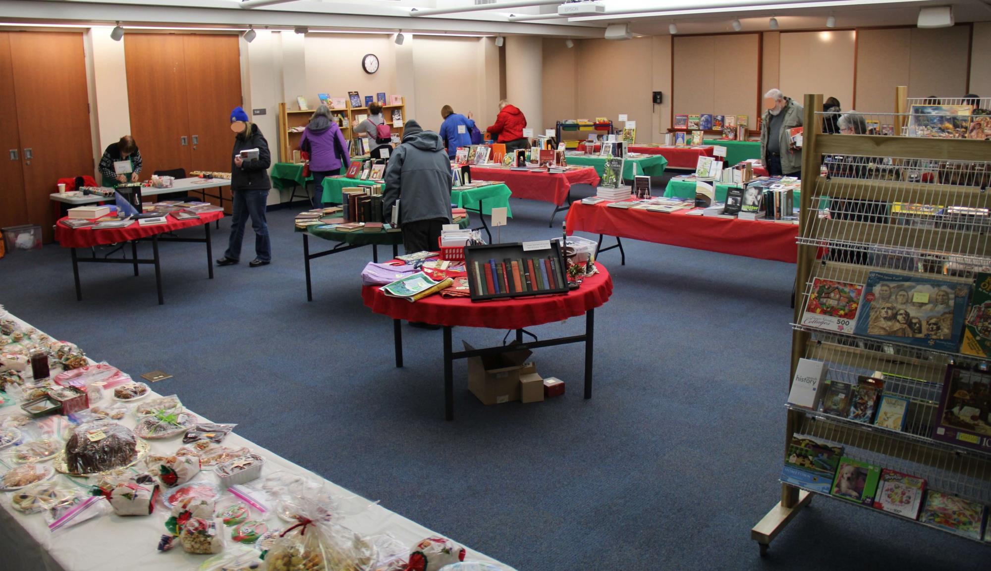 Gift Quality Book and Bake Sale in the library auditorium with tables around that have different items on them with red table clothes